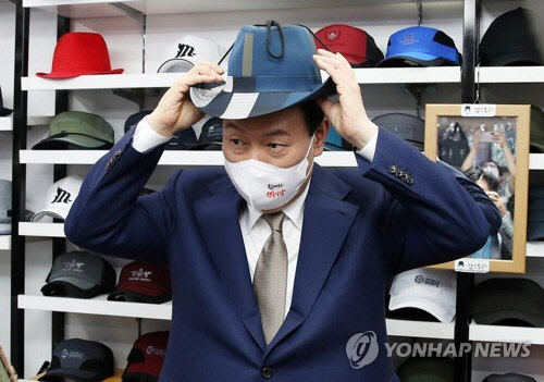 윤석열 대통령이 26일 오후 대구 중구 서문시장 내 모자 가게를 방문, 모자를 써보며 상인들과 대화하고 있다. 연합뉴스